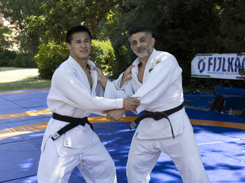 Attività di judo inclusivo durante una dimostrazione sportiva, con atleta DONG DONG CAMANNI e tecnico impegnati in un esercizio sul tatami all’aperto